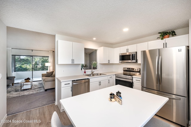 kitchen with white cabinets, stainless steel appliances, light hardwood / wood-style flooring, and sink