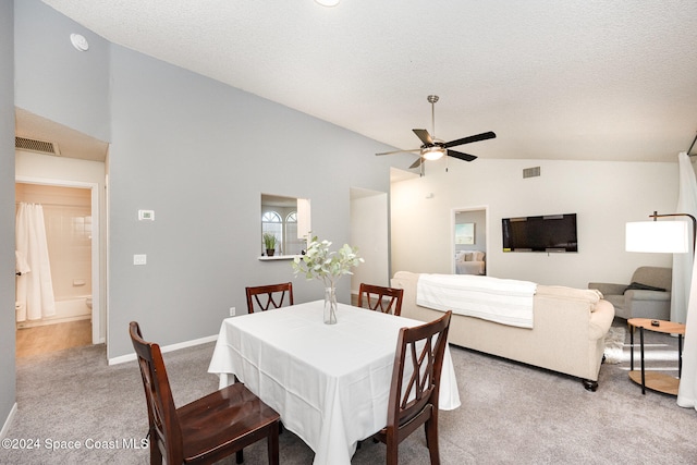 carpeted dining area with a textured ceiling, ceiling fan, and vaulted ceiling