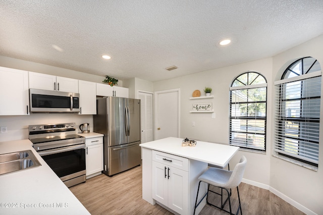 kitchen featuring a textured ceiling, light wood-type flooring, white cabinetry, and stainless steel appliances