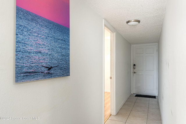 hallway featuring light tile patterned floors and a textured ceiling