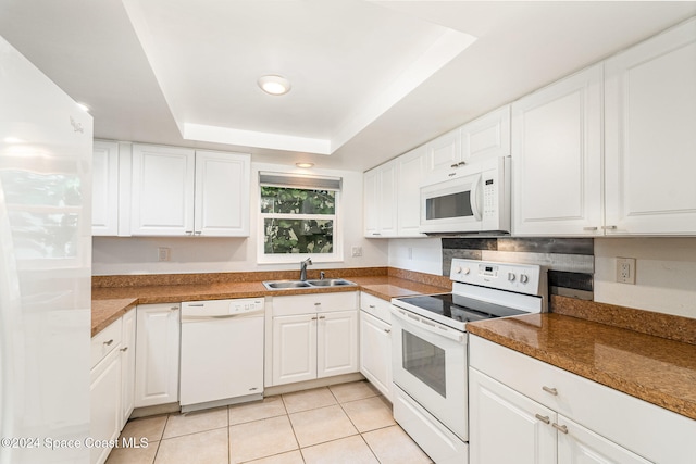 kitchen featuring white cabinetry, sink, a raised ceiling, white appliances, and light tile patterned floors