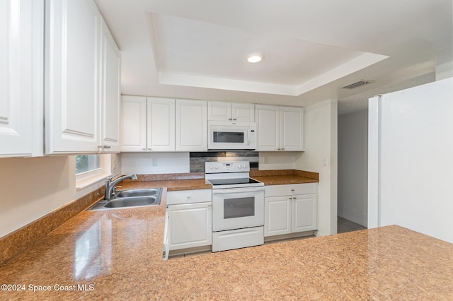 kitchen featuring white cabinetry, white appliances, sink, and a tray ceiling