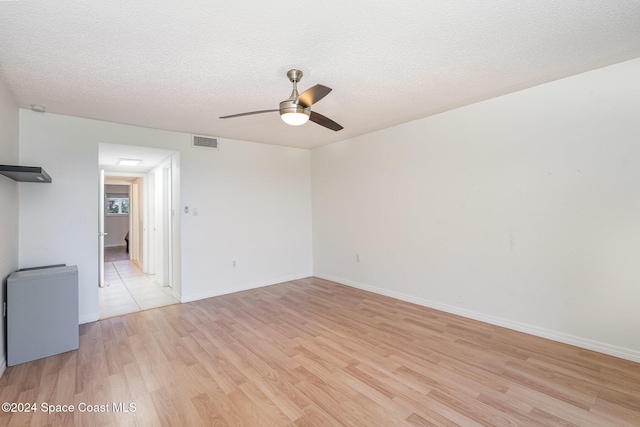 unfurnished room with a textured ceiling, light wood-type flooring, and ceiling fan