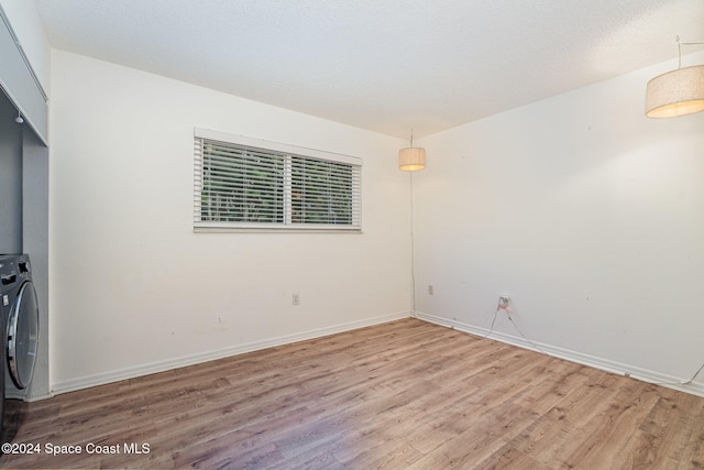 unfurnished room with hardwood / wood-style floors, a textured ceiling, and washer / dryer