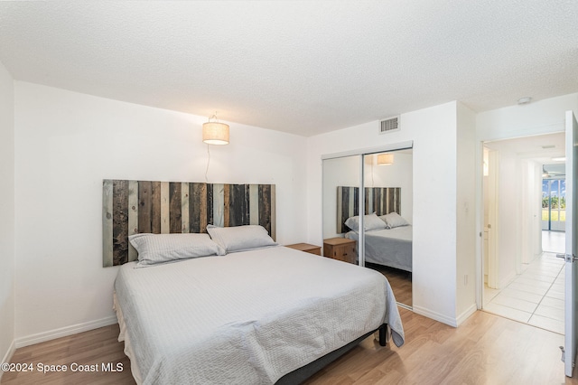 bedroom featuring hardwood / wood-style floors, a textured ceiling, and a closet