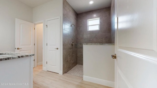 bathroom with tiled shower, vanity, and hardwood / wood-style flooring