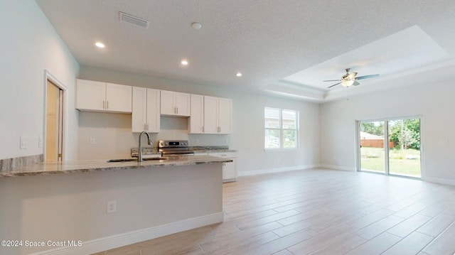 kitchen featuring ceiling fan, light wood-type flooring, light stone countertops, stainless steel range, and white cabinetry