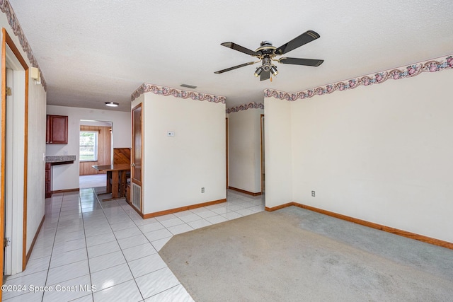 empty room featuring ceiling fan, light tile patterned floors, and a textured ceiling