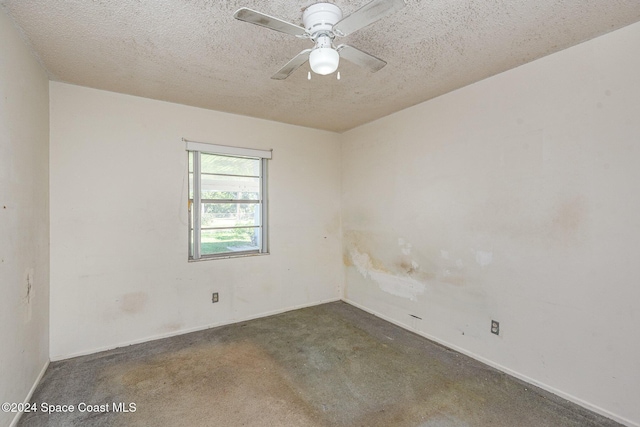 spare room with dark colored carpet, ceiling fan, and a textured ceiling