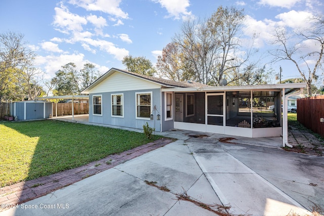 back of property featuring a sunroom, a yard, a patio, and a storage unit