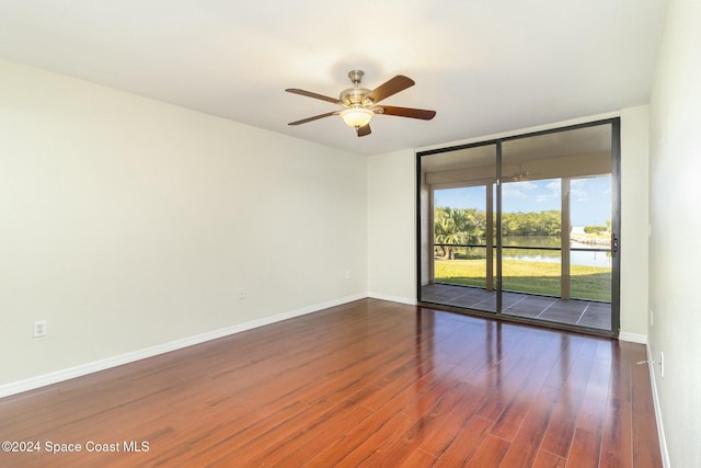 empty room featuring expansive windows, dark wood finished floors, baseboards, and ceiling fan