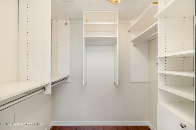 walk in closet with dark wood-type flooring