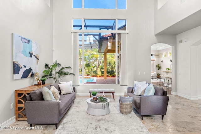 living room with a towering ceiling and ceiling fan