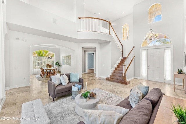 living room featuring a healthy amount of sunlight, a towering ceiling, and a chandelier