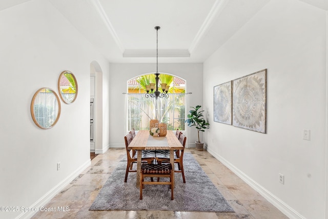 dining space with a raised ceiling and a chandelier