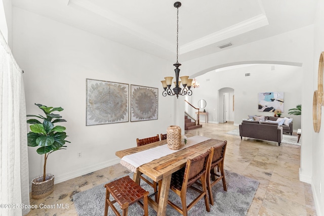 dining area with ornamental molding, a tray ceiling, and a notable chandelier