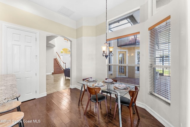 dining space with dark hardwood / wood-style flooring and an inviting chandelier