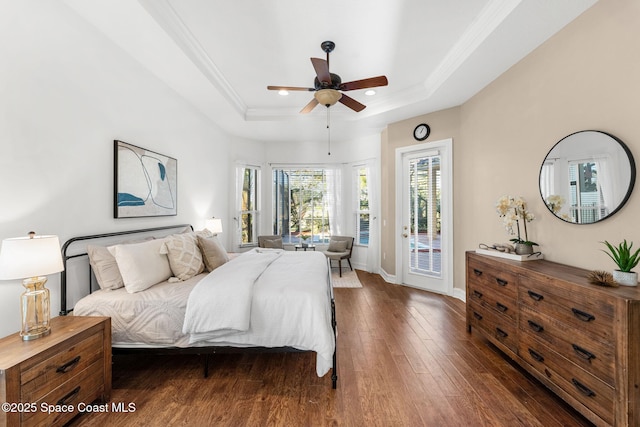 bedroom featuring dark wood-type flooring, access to outside, crown molding, ceiling fan, and a tray ceiling