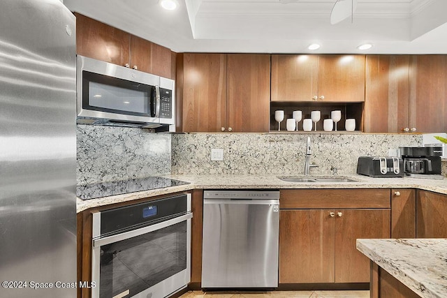 kitchen with decorative backsplash, light stone counters, ornamental molding, stainless steel appliances, and sink