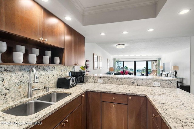 kitchen featuring light stone counters, kitchen peninsula, sink, and tasteful backsplash