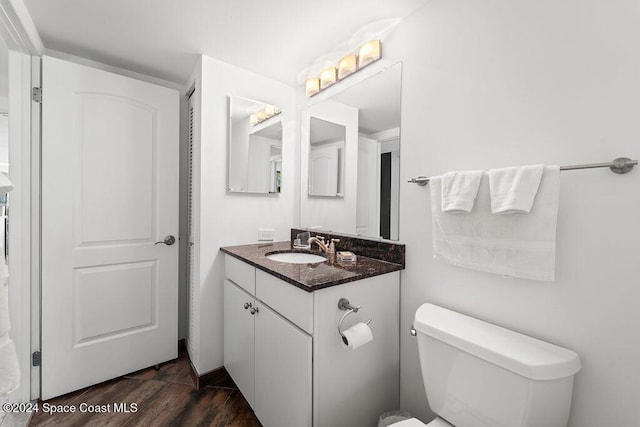 bathroom with wood-type flooring, vanity, and toilet