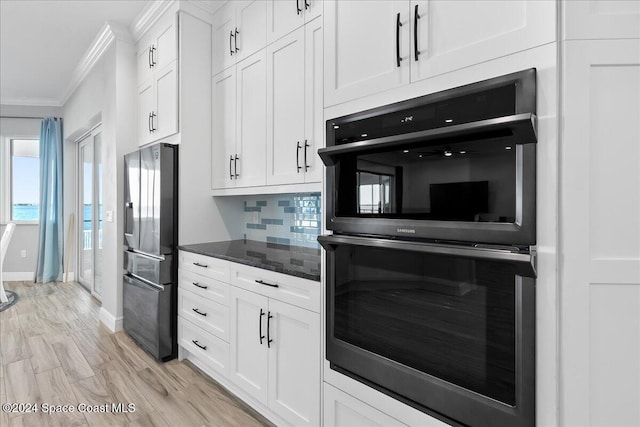 kitchen featuring ornamental molding, dobule oven black, white cabinetry, freestanding refrigerator, and decorative backsplash