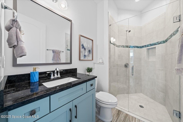 full bathroom featuring wood finished floors, toilet, a stall shower, and vanity