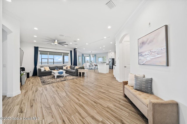 living room featuring baseboards, visible vents, light wood-style flooring, recessed lighting, and ornamental molding