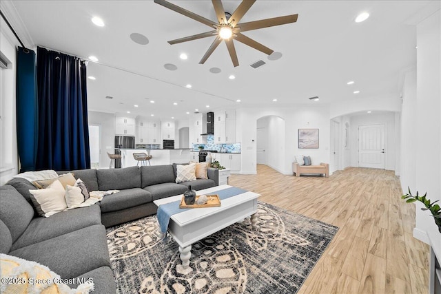 living area with visible vents, light wood finished floors, recessed lighting, arched walkways, and ceiling fan