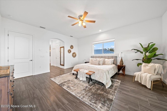 bedroom with arched walkways, visible vents, baseboards, and dark wood-style flooring