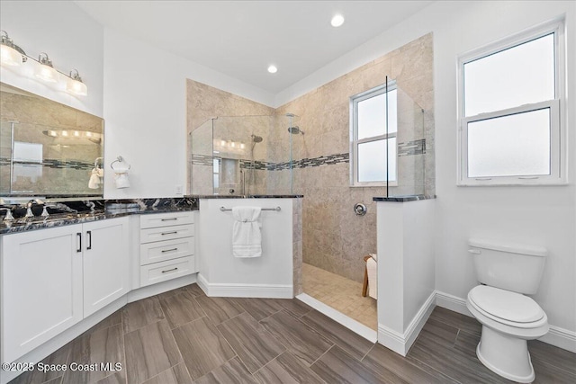 bathroom featuring toilet, a walk in shower, recessed lighting, baseboards, and vanity