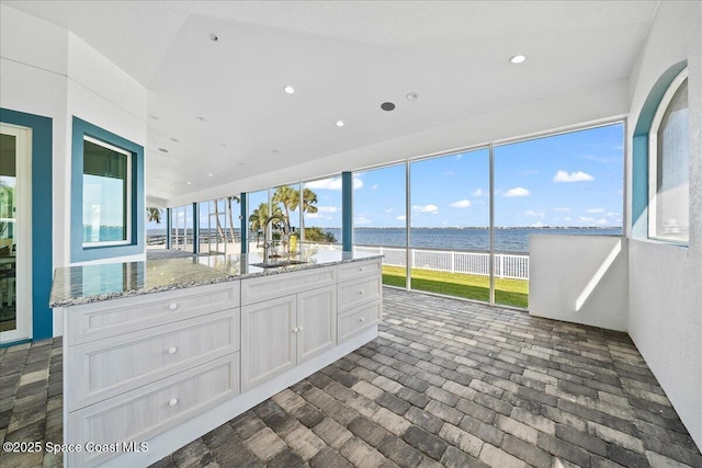 unfurnished sunroom with a sink and a water view