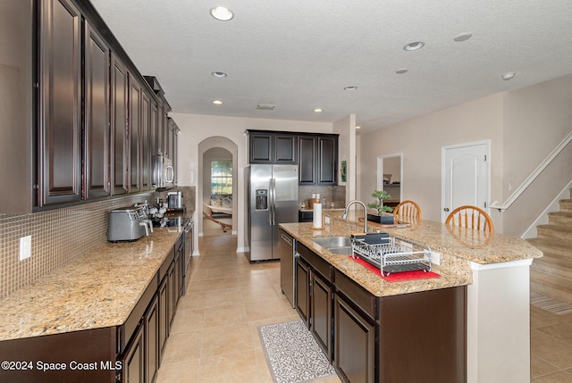 kitchen featuring sink, stainless steel appliances, backsplash, and an island with sink