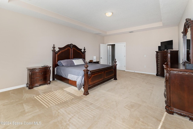 carpeted bedroom featuring a textured ceiling and a raised ceiling