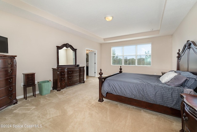 bedroom featuring a textured ceiling, a raised ceiling, and light carpet