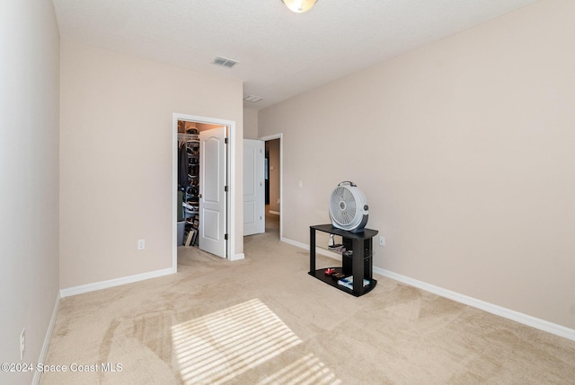 bedroom with a walk in closet and light colored carpet