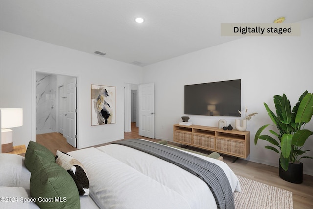 bedroom featuring ensuite bathroom and light wood-type flooring