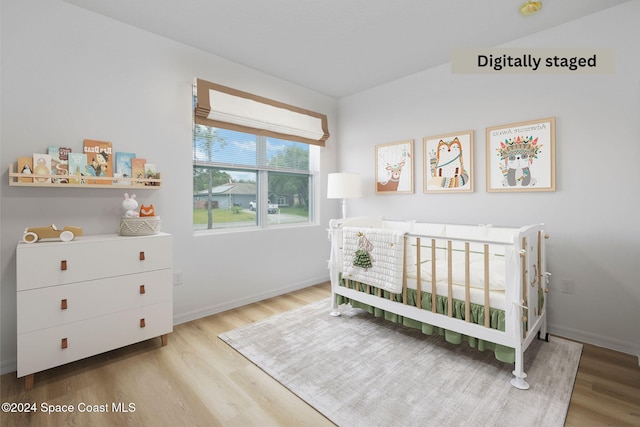 bedroom with light hardwood / wood-style floors and a crib