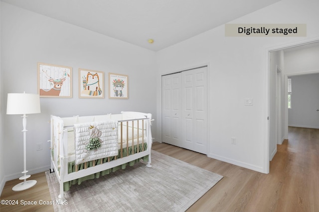 unfurnished bedroom featuring a crib, light wood-type flooring, and a closet