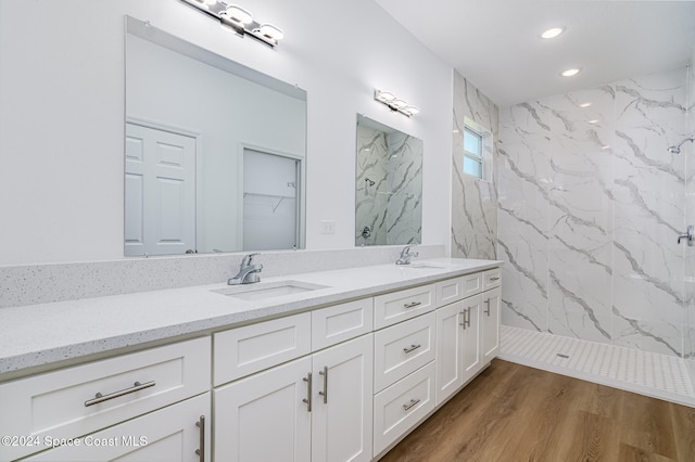 bathroom with hardwood / wood-style floors, vanity, and tiled shower