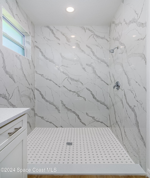 bathroom with vanity and tiled shower