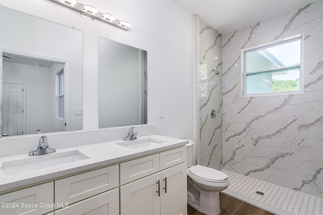 bathroom with a tile shower, vanity, hardwood / wood-style flooring, and toilet