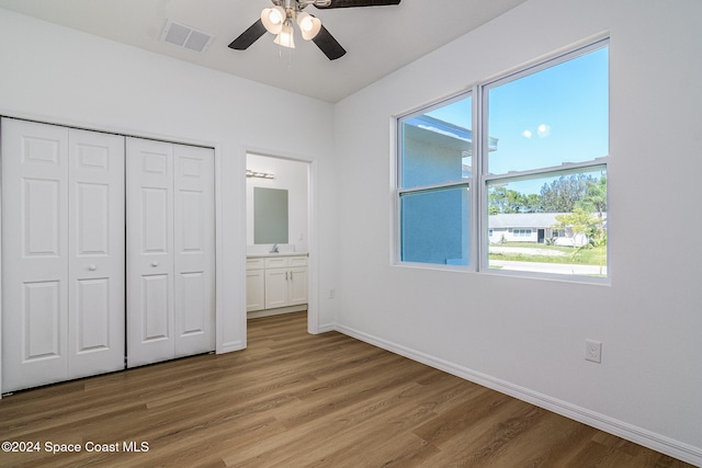 unfurnished bedroom featuring a closet, ceiling fan, hardwood / wood-style floors, and ensuite bathroom