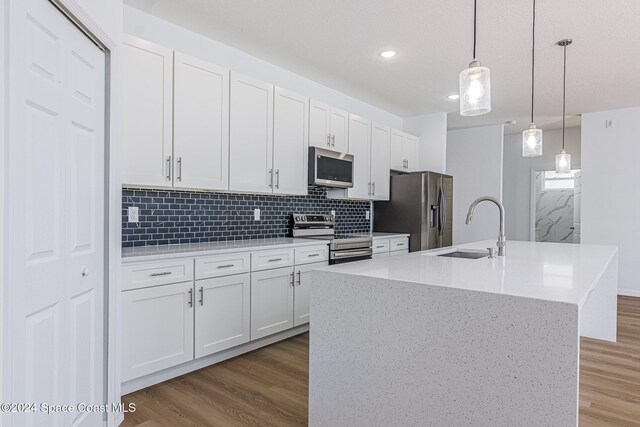 kitchen with white cabinetry, sink, pendant lighting, a center island with sink, and appliances with stainless steel finishes