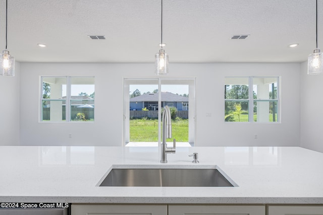 kitchen with pendant lighting, light stone countertops, and sink