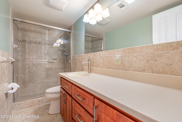 bathroom with vanity, toilet, tile walls, and a shower with shower door