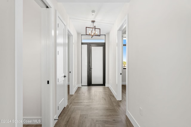 hallway with parquet floors and an inviting chandelier