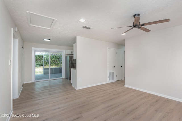 empty room with ceiling fan, light wood-type flooring, and a textured ceiling