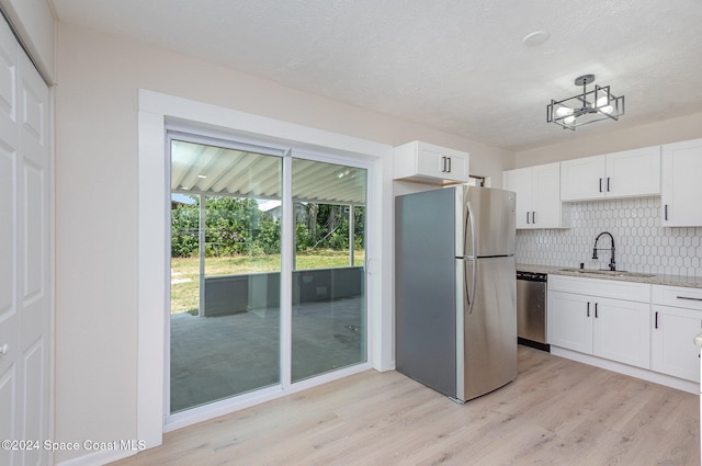 kitchen with sink, white cabinets, light hardwood / wood-style flooring, and appliances with stainless steel finishes