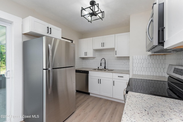 kitchen featuring appliances with stainless steel finishes, light wood-type flooring, white cabinetry, and sink